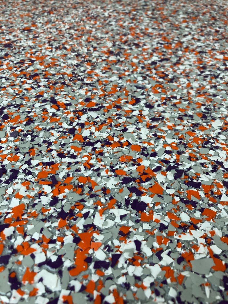 Close-up of a speckled epoxy floor with orange, gray, white, and black chips.