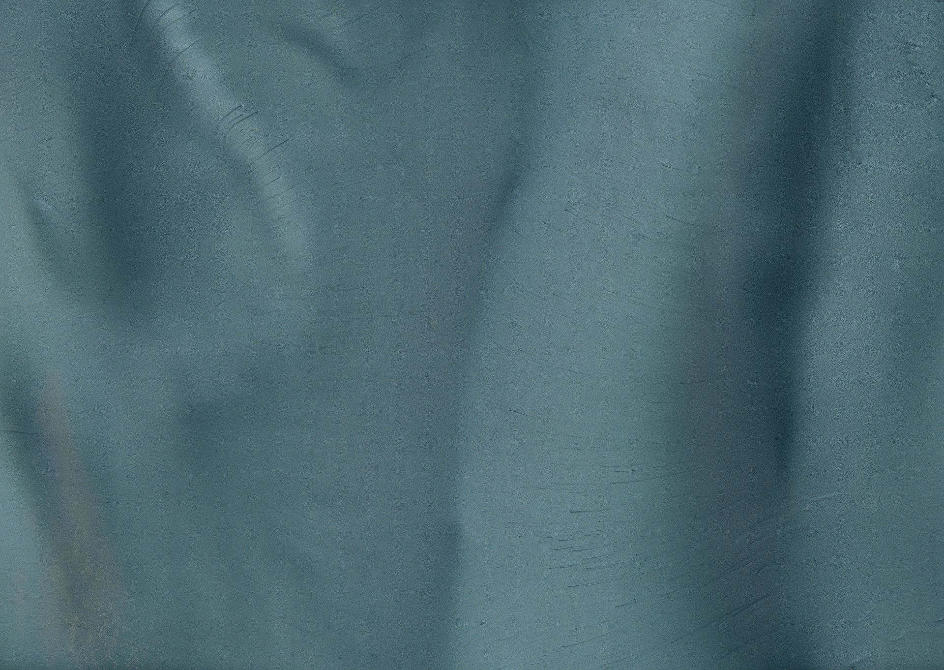 Teal-colored fabric with soft folds and subtle texture.