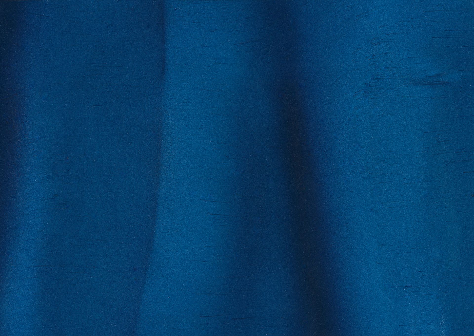 Blue fabric with subtle texture and folds, illuminated with a shadowed area.