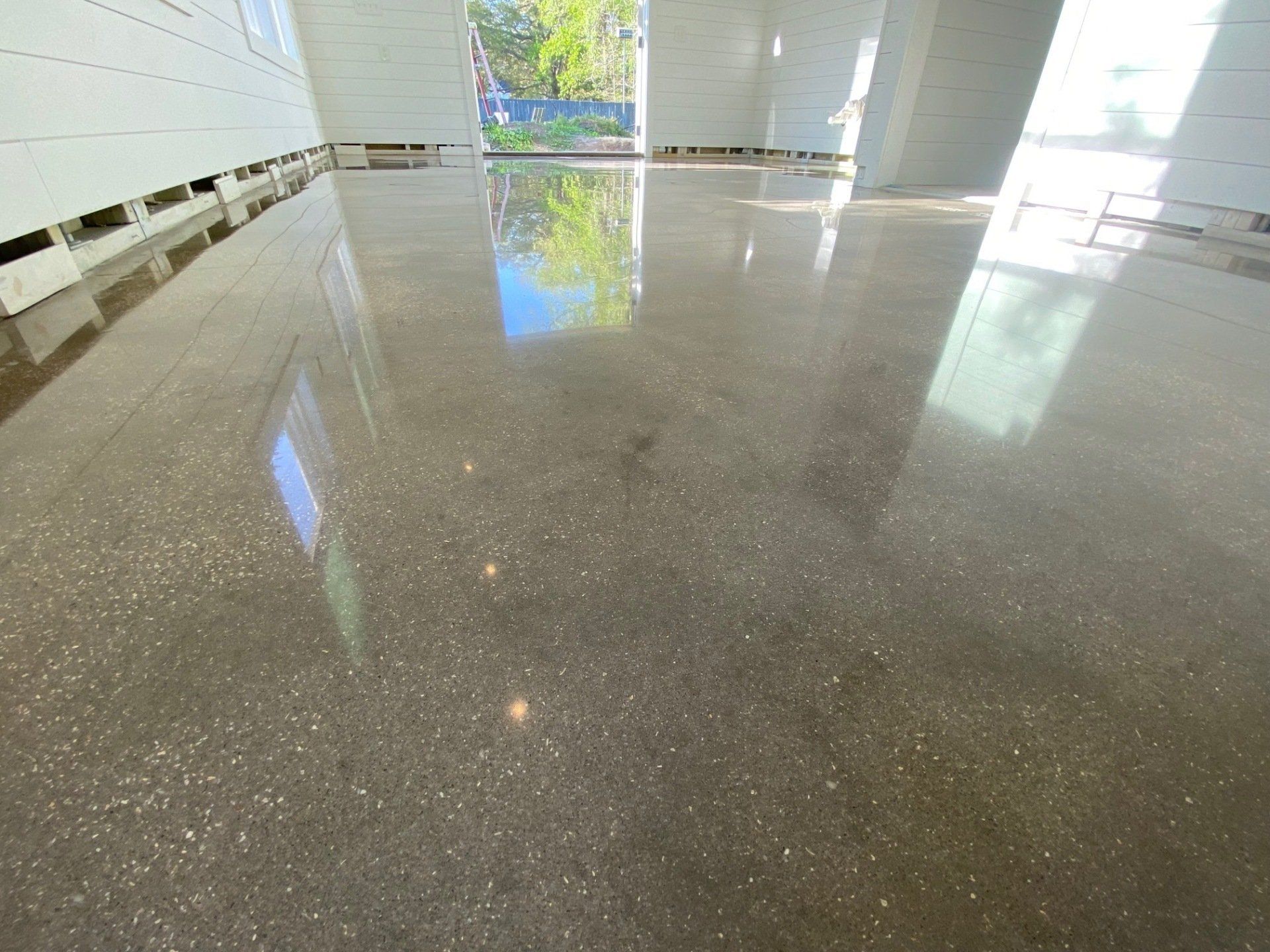 Polished concrete floor reflects sunlight and the surrounding environment.