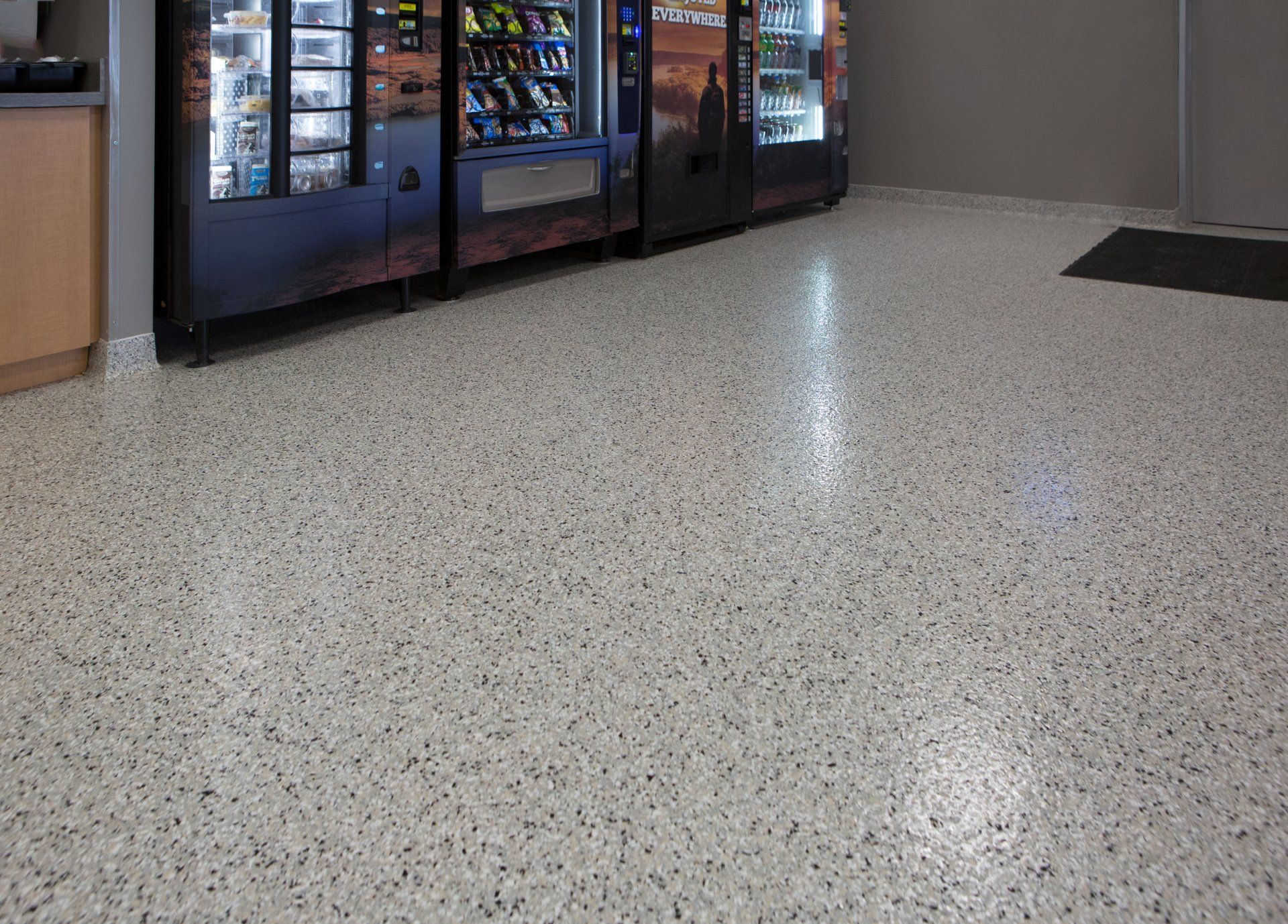 Terrazzo flooring in a room with vending machines along one wall. The floor is speckled with various dark and light colors.