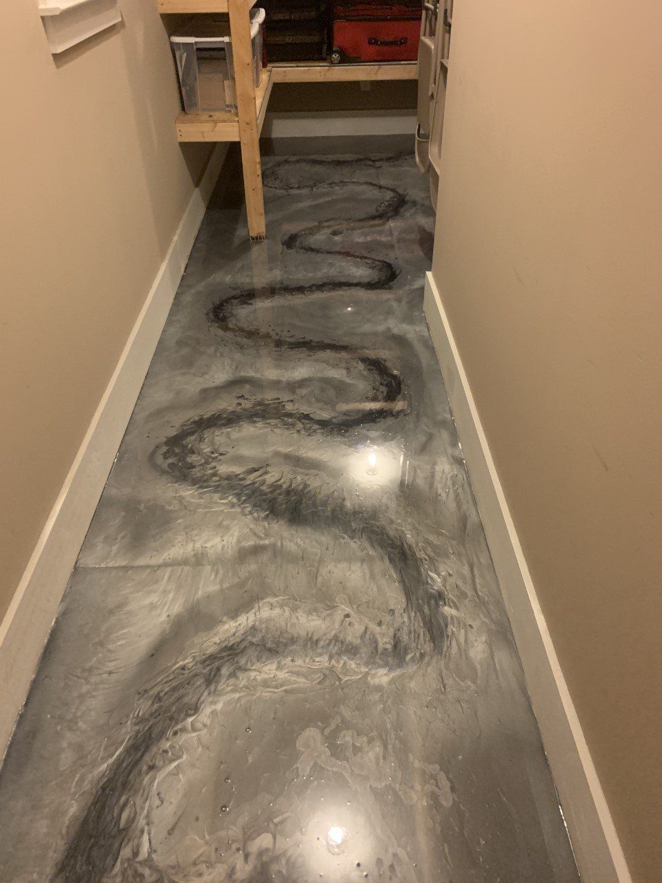 Narrow hallway with shiny, silver epoxy flooring with a dark, winding river-like design.