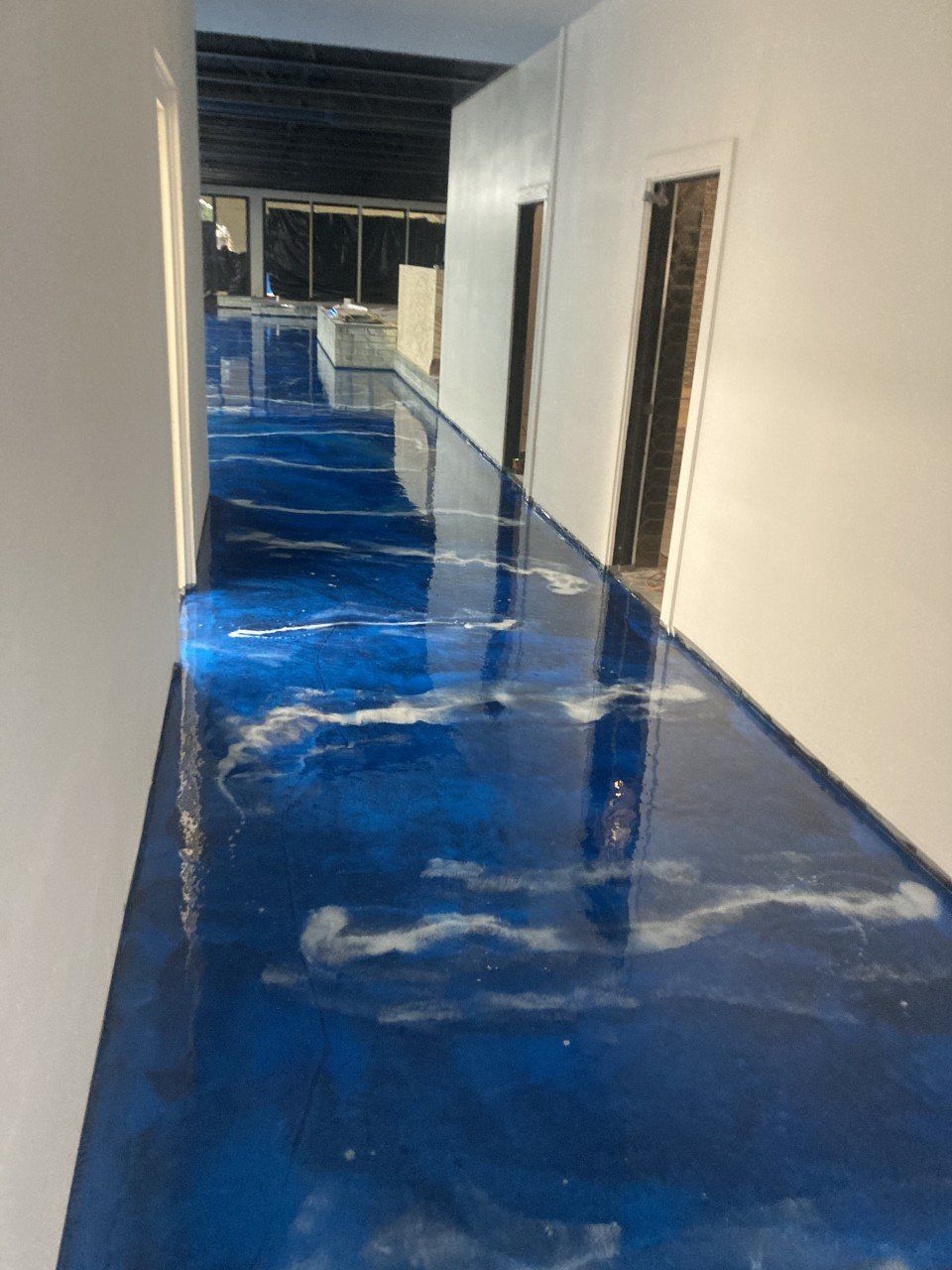 A long hallway with a shiny blue epoxy floor, resembling an ocean with white swirls.