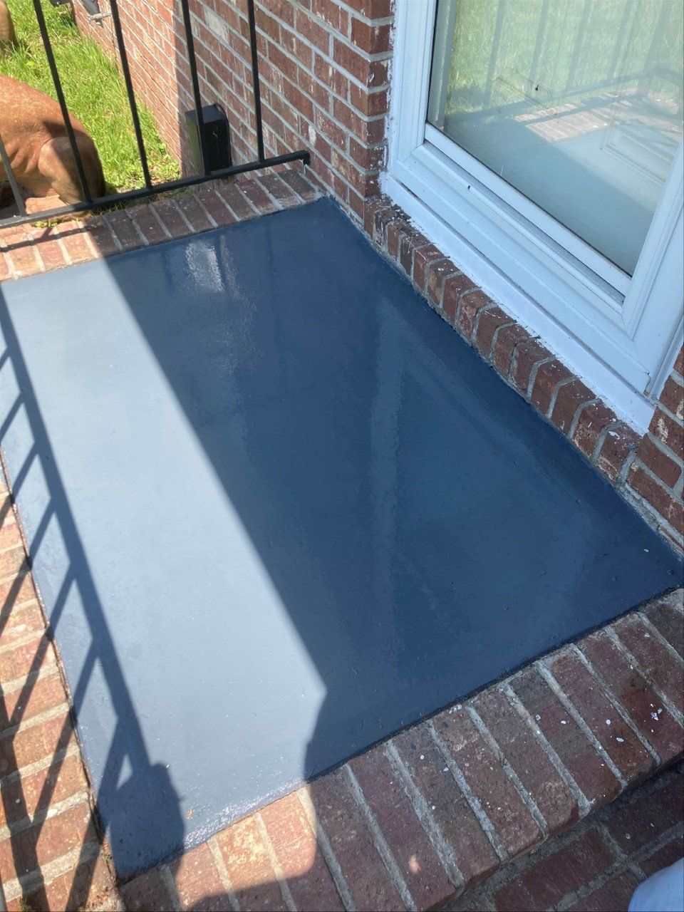 Dark blue painted concrete surface set within a brick border, next to a white window.