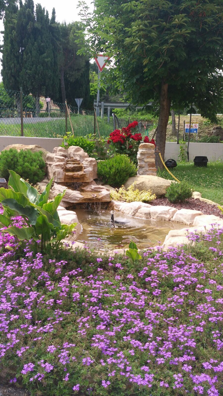 C'è una cascata in mezzo a un giardino con fiori viola.