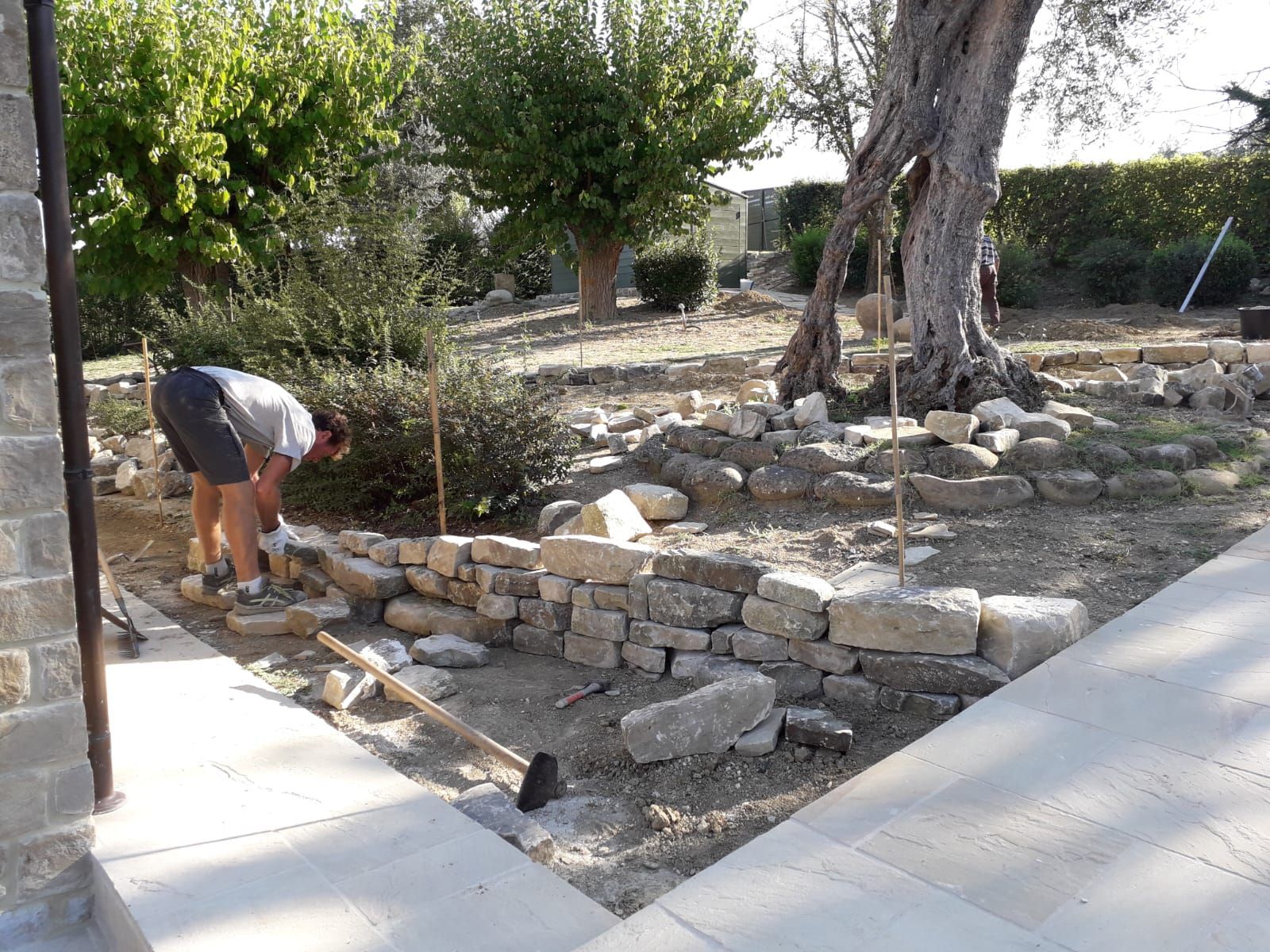 Un uomo sta lavorando su un muro di pietra in un giardino