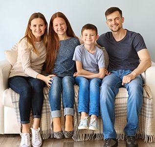 A family is sitting on a couch posing for a picture.