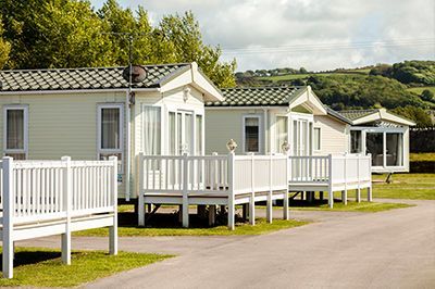 A row of mobile homes with white decks in a park.