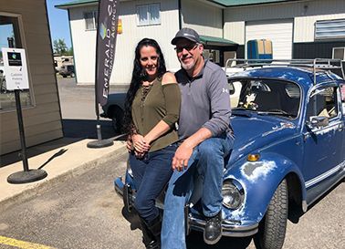 A man and a woman are standing next to a blue car.
