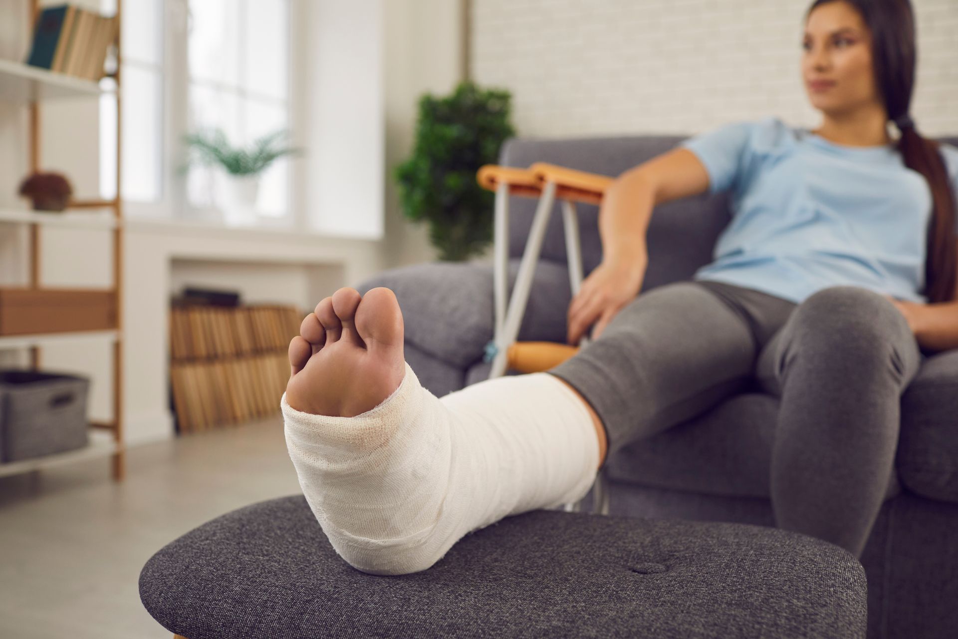 A woman with a cast on her leg is sitting on a couch.