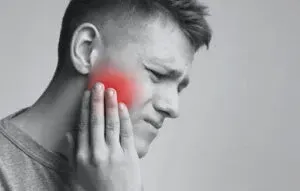 A man is holding his face in pain because of a toothache.