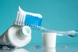 A tube of toothpaste and a toothbrush on a table.