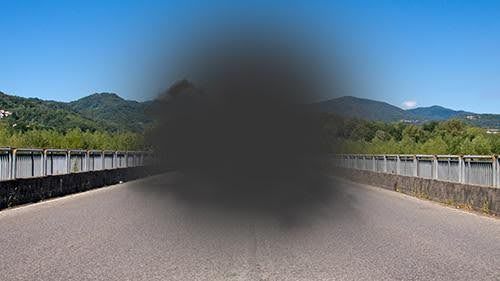 A person with a blurred vision is driving down a road.