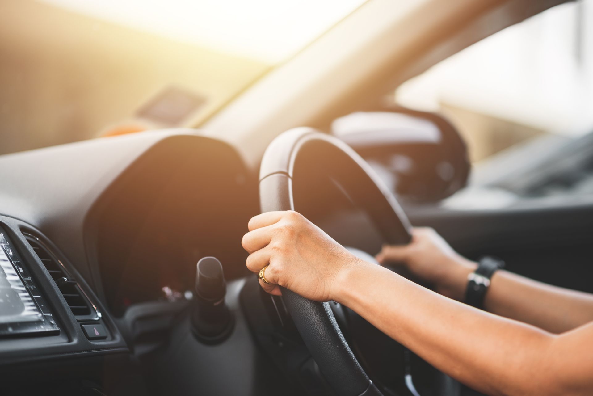 A woman is driving a car with her hands on the steering wheel