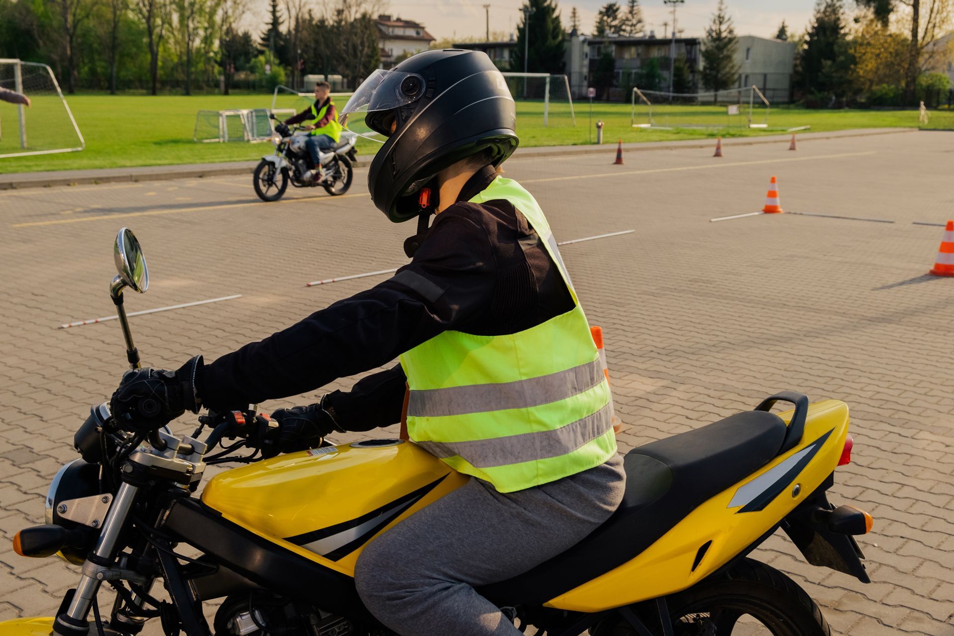 A person is riding a yellow motorcycle on a brick road