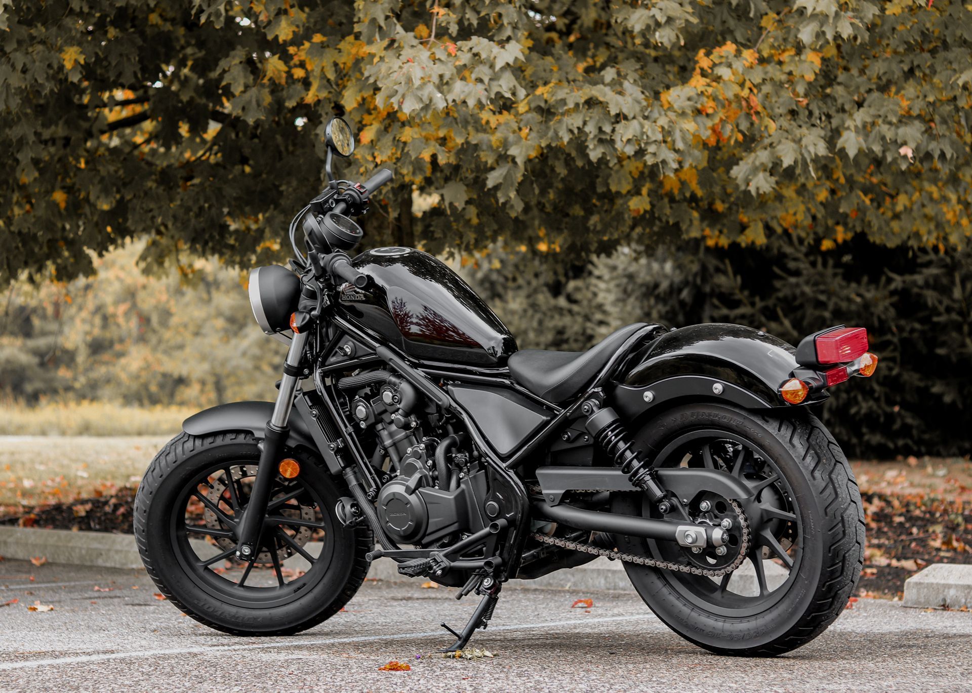 A black motorcycle is parked on the side of the road next to a tree