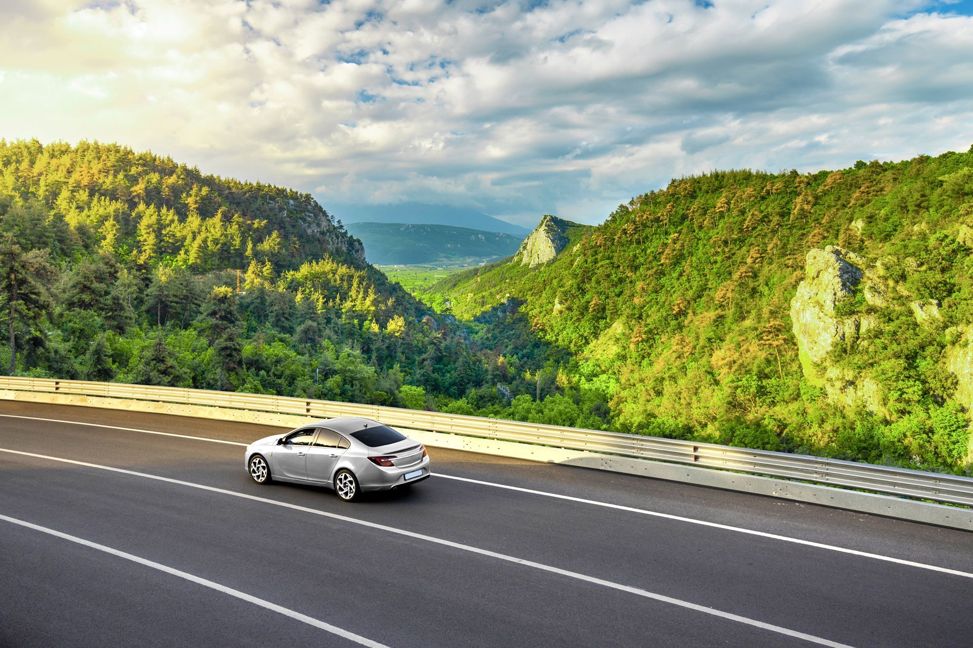 A car is driving down a road in the mountains