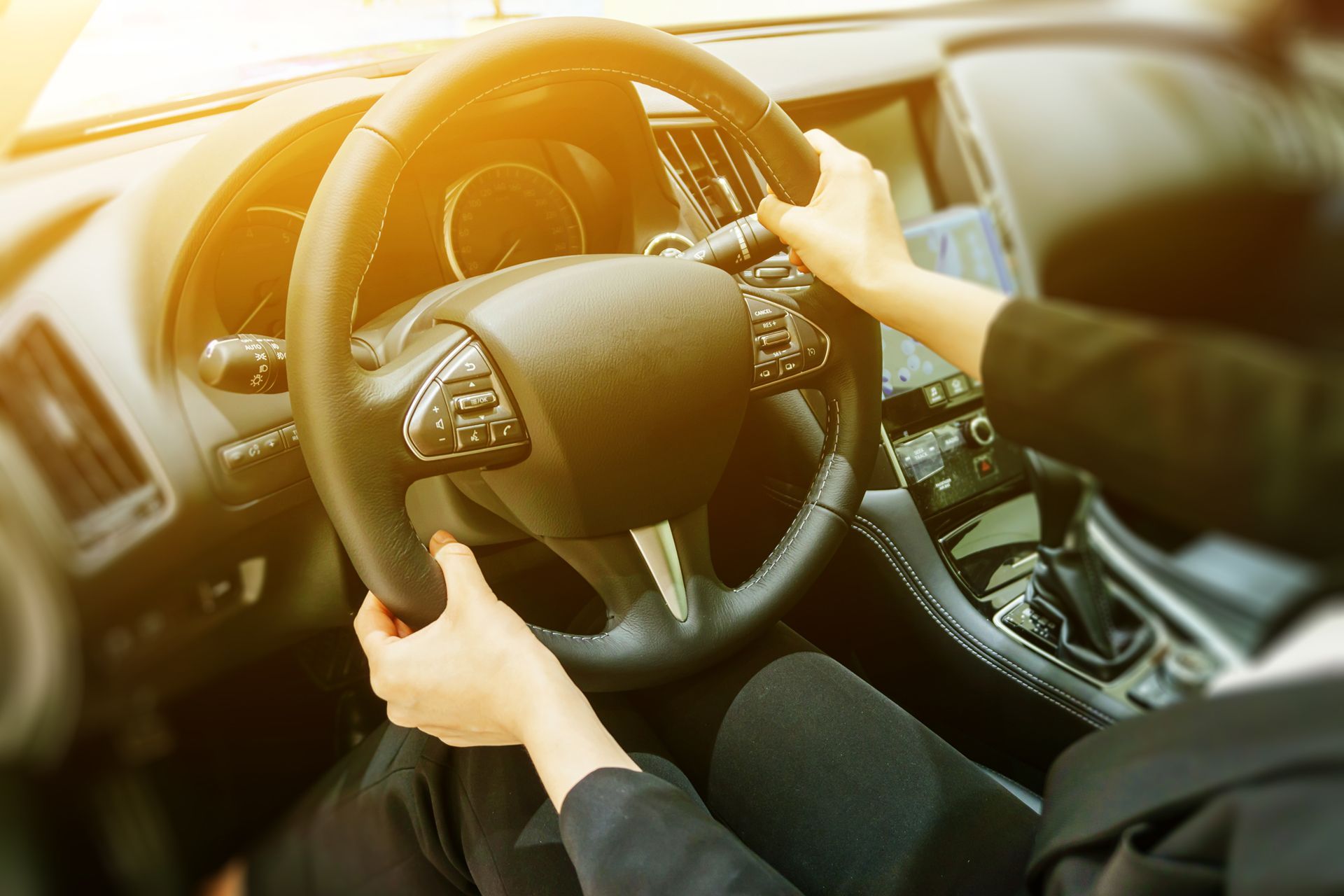 A woman is driving a car with her hands on the steering wheel