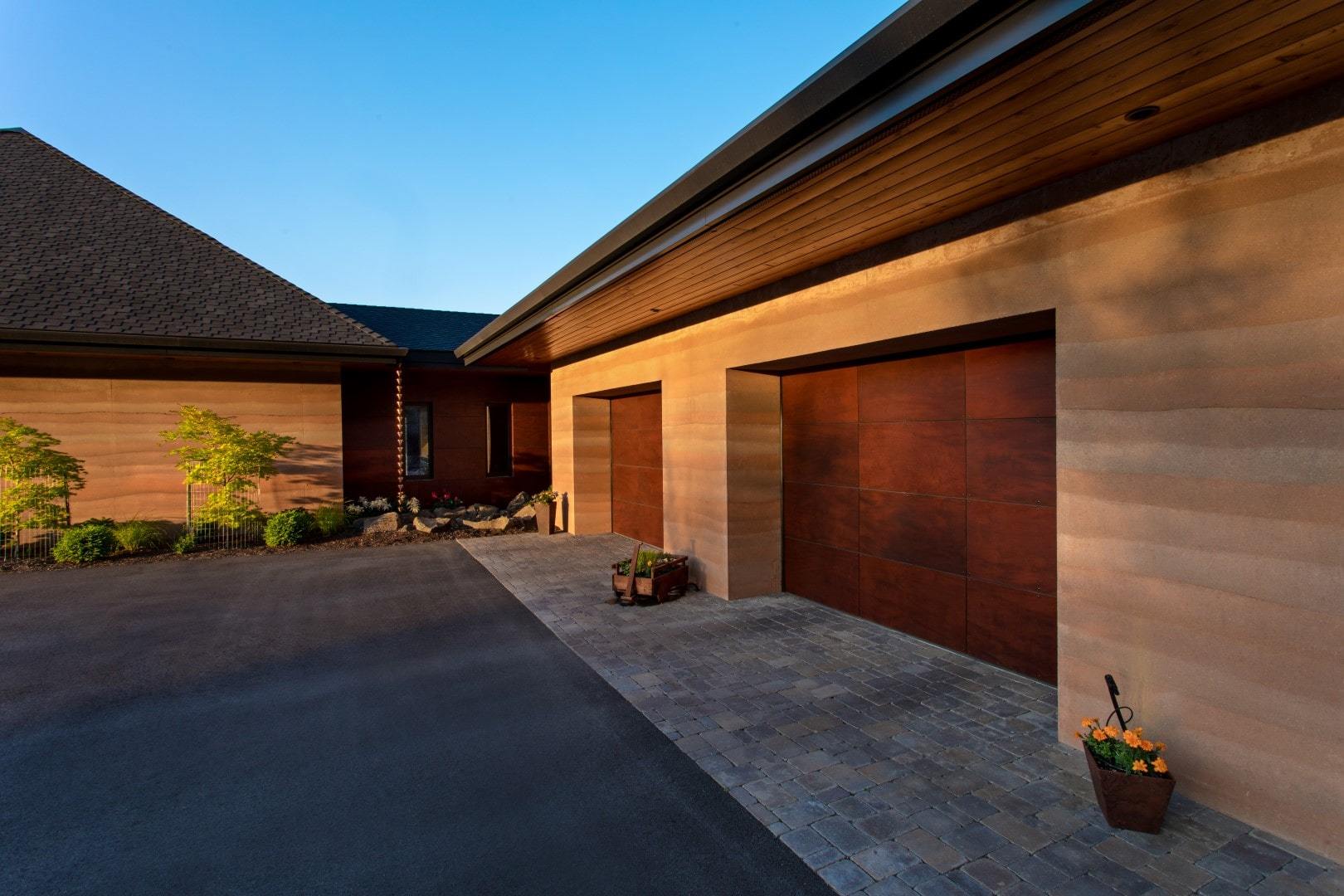 Exterior of a Passiv haus with r 2 car garage made out of SIREWALL, rammed earth.