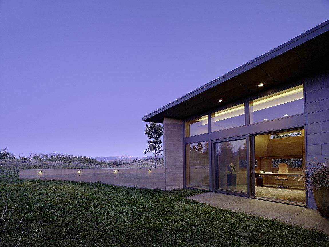 The exterior SIREWALL home at dusk with large, metal windows.