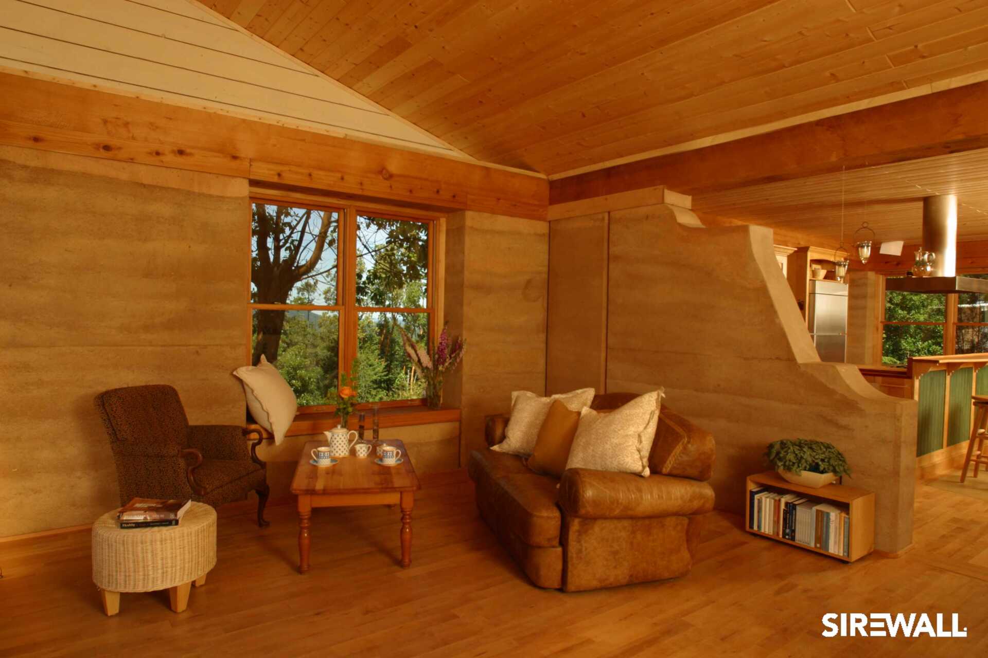 Warm interior of a SIREWALL home's living room with rammed earth walls and cozy natural finishes.