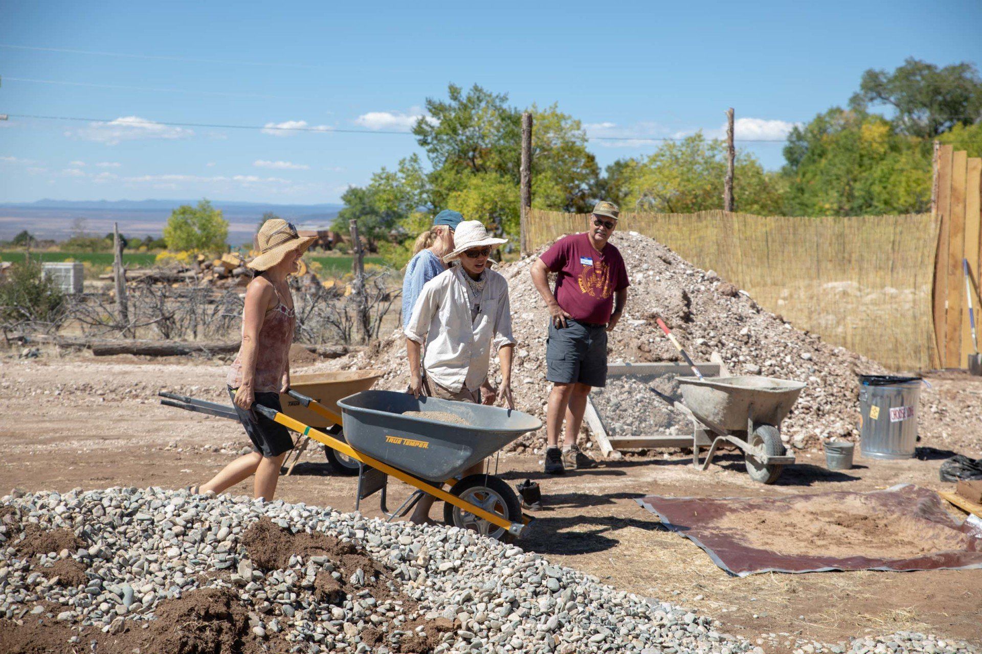 Four Eco Build Lab Workshop participants on a jobsite with gravel and wheelbarrows.