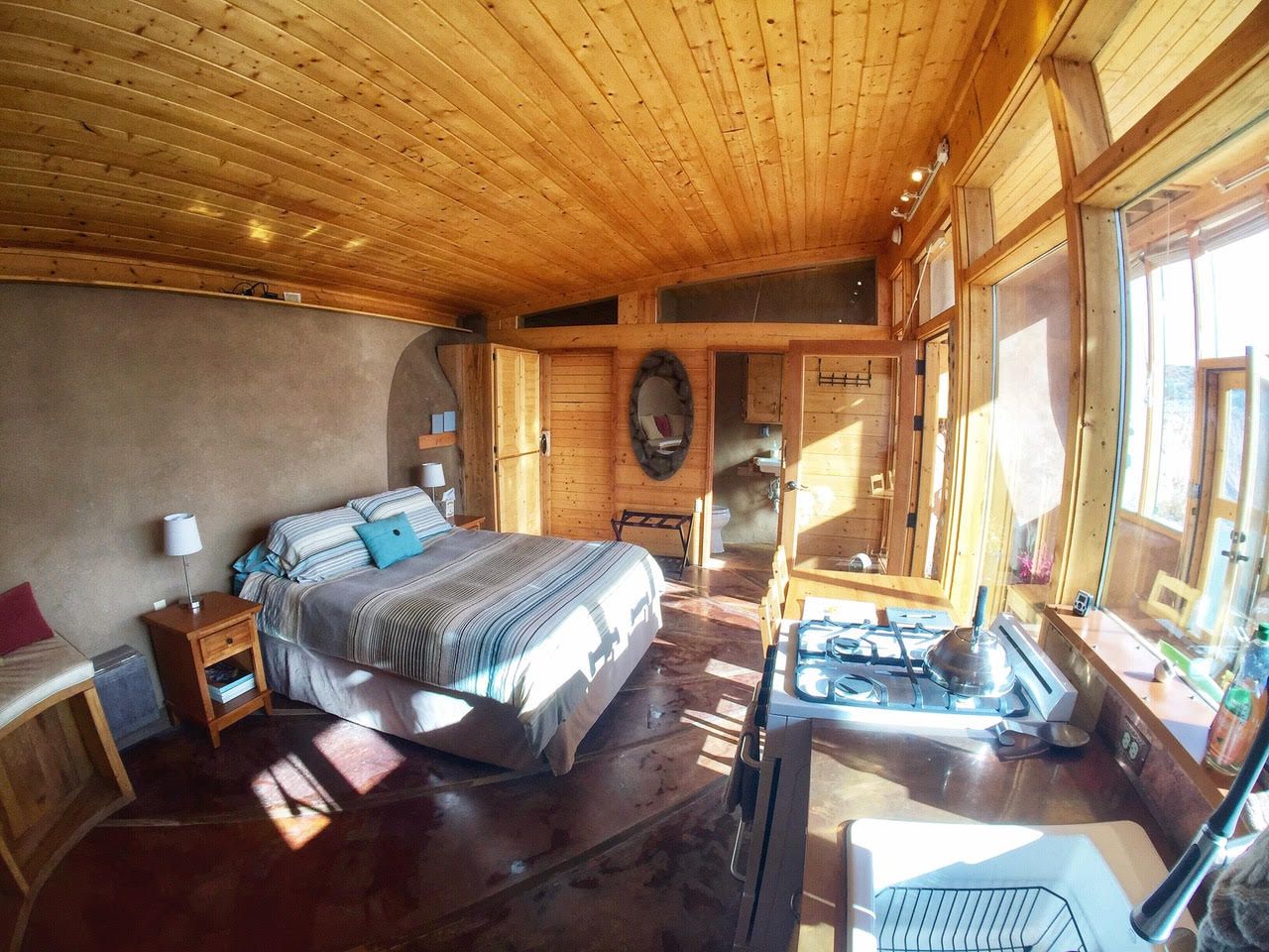 Interior of a small, 500square foot studio earthship with bed and kitchen.