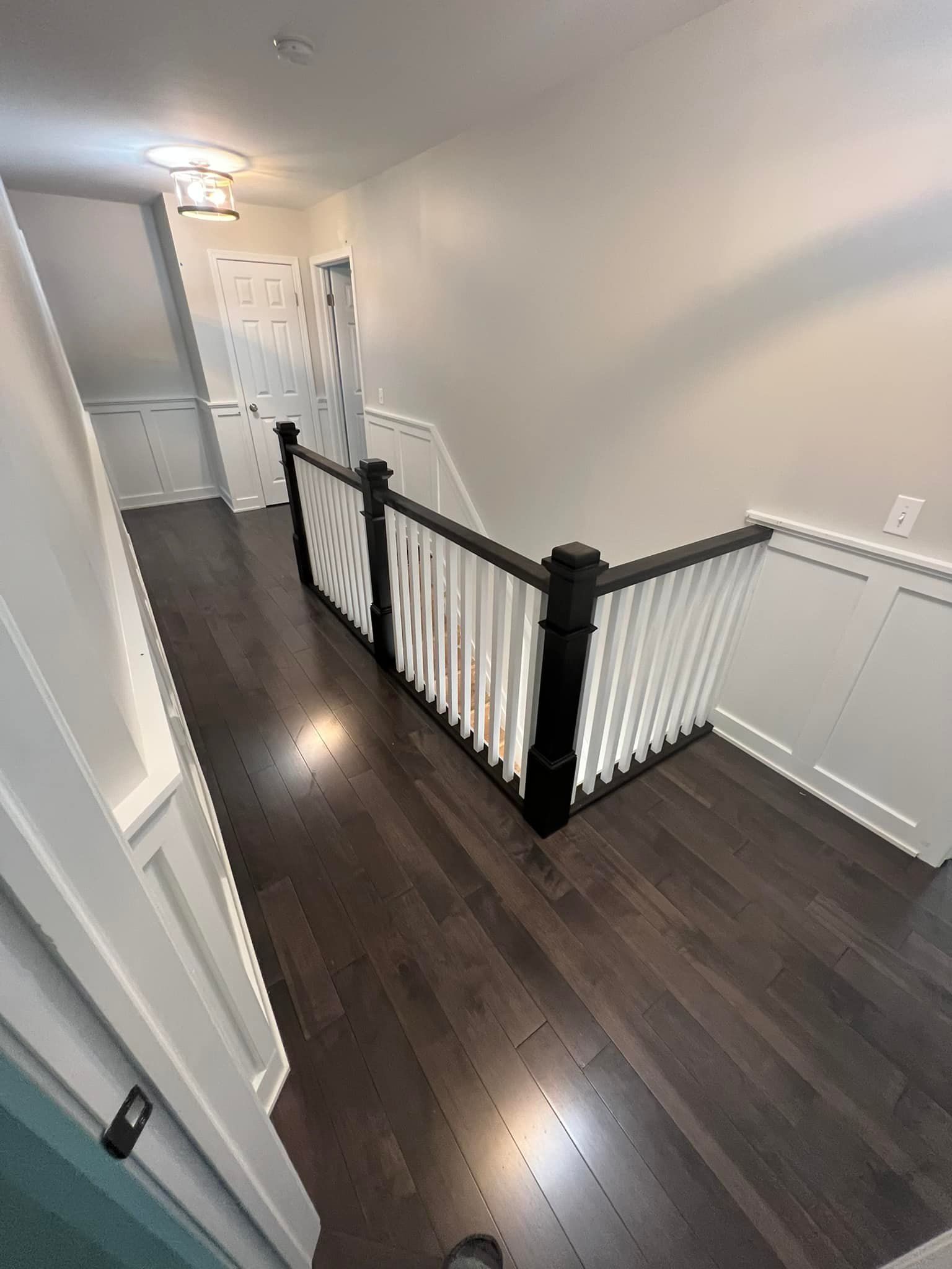 A staircase with a black railing and a white railing in a house.