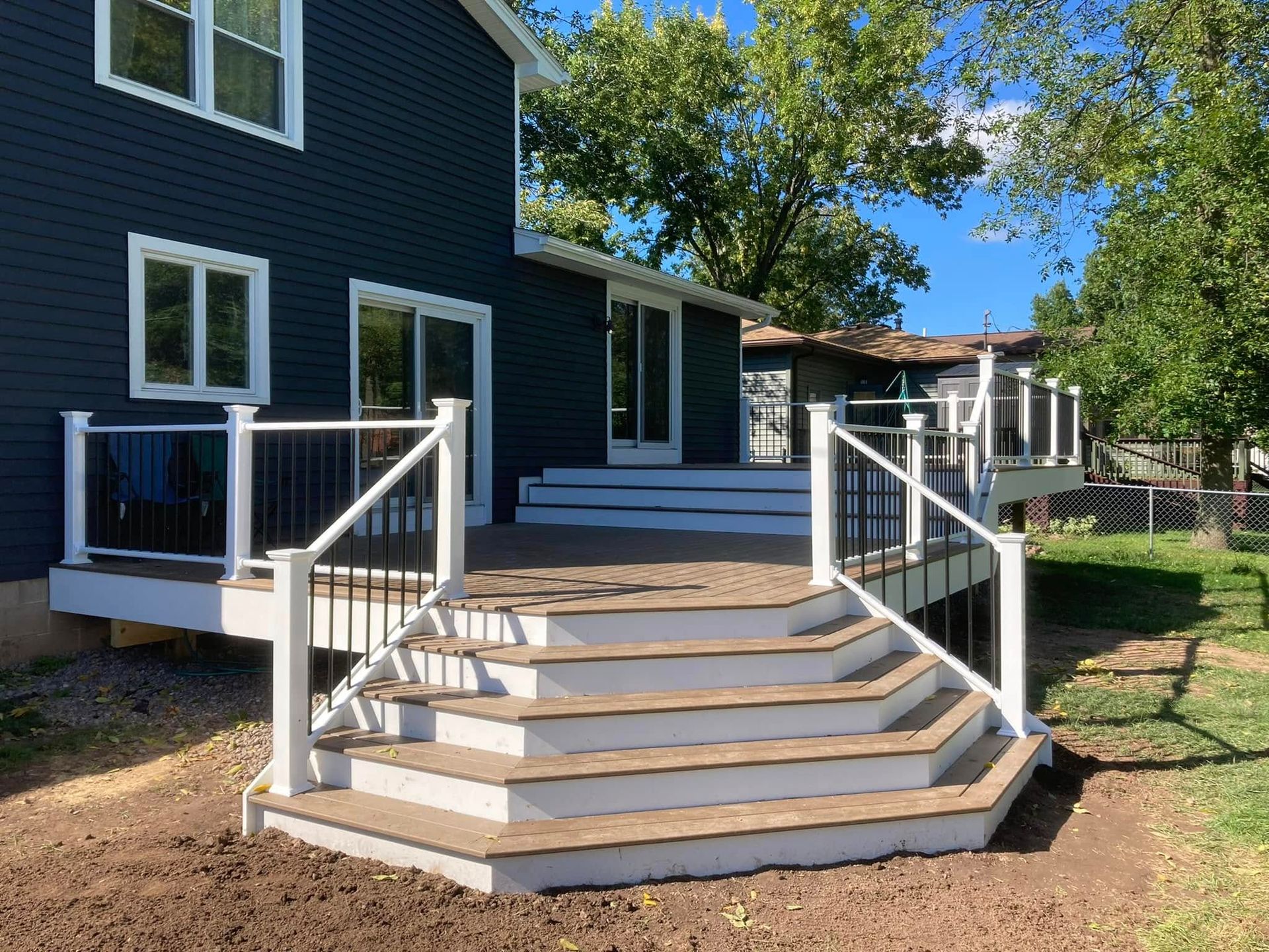 A blue house with a deck and stairs in front of it.