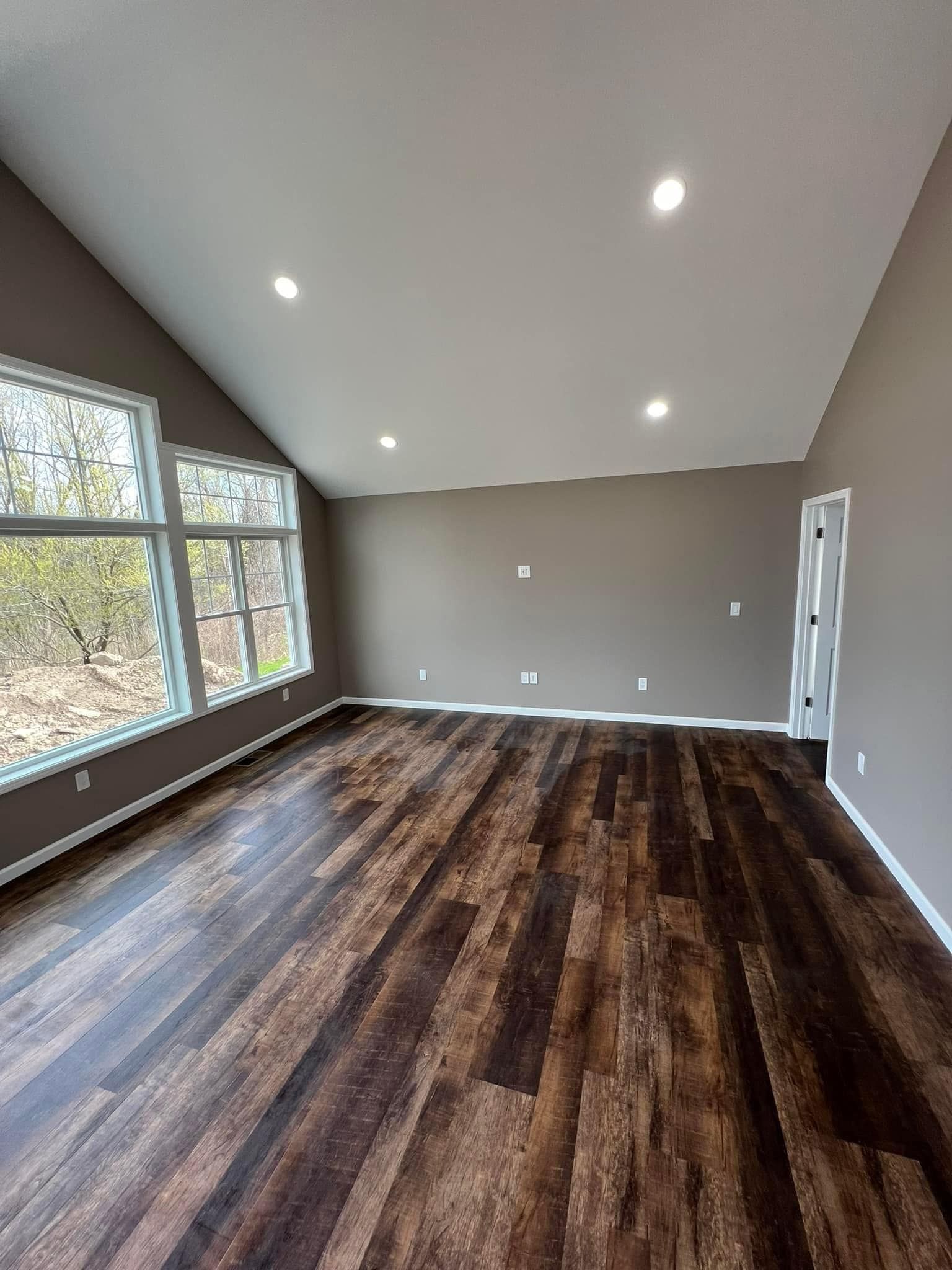An empty living room with hardwood floors and lots of windows.