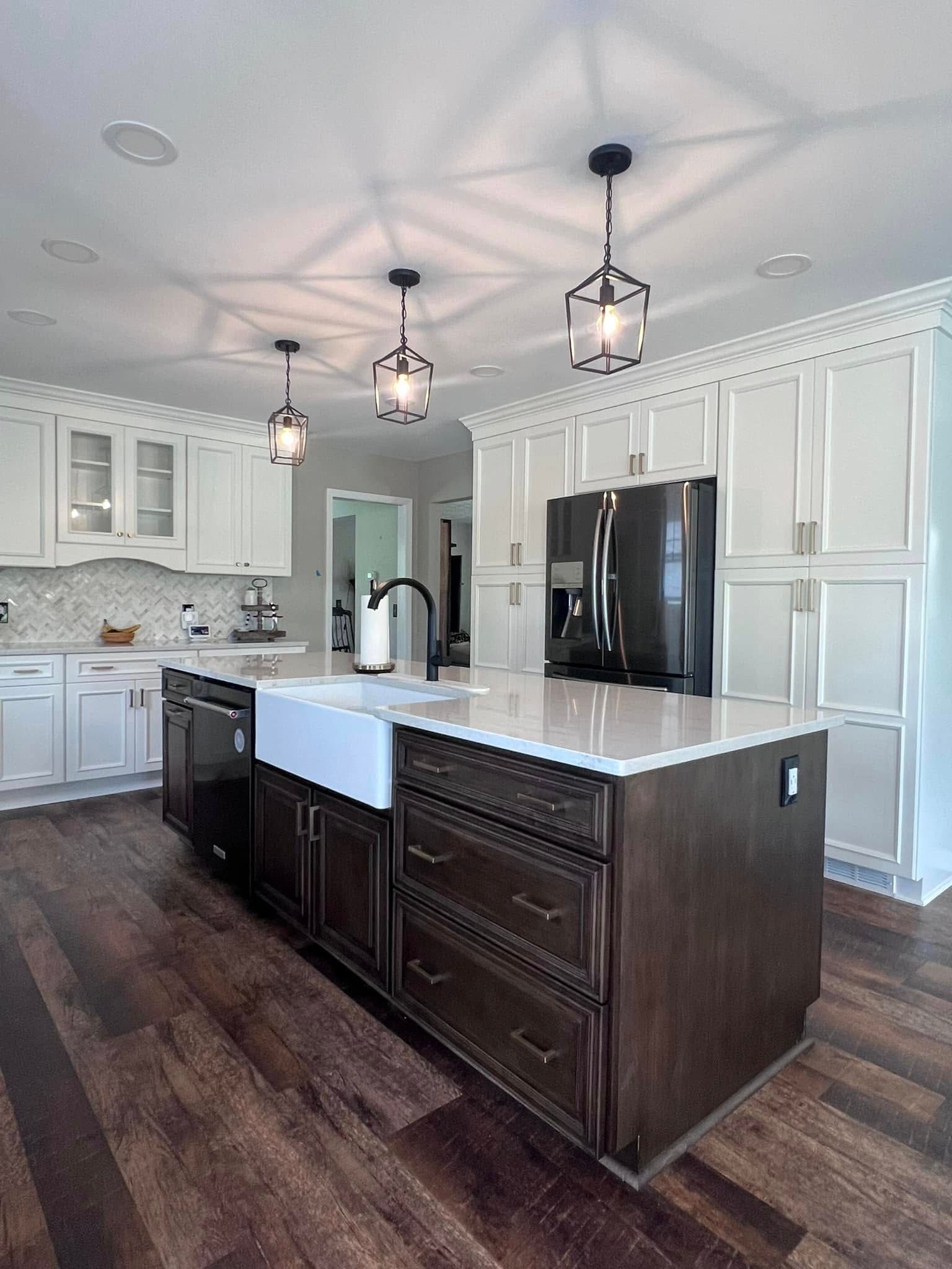 A kitchen with a large island , sink , refrigerator and dishwasher.