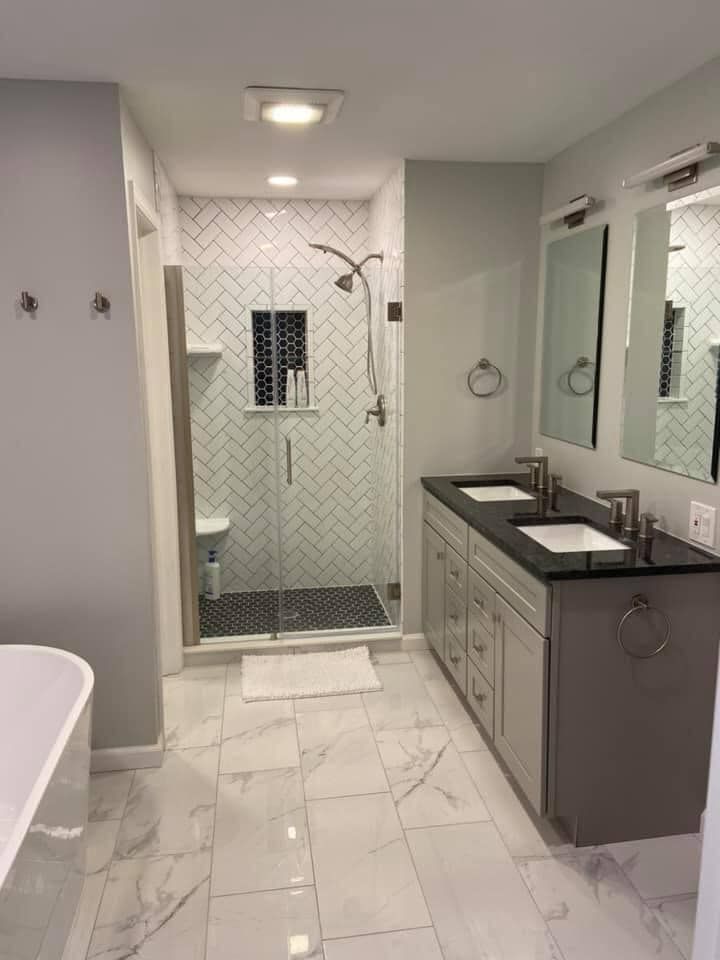 A bathroom with two sinks and a walk in shower.
