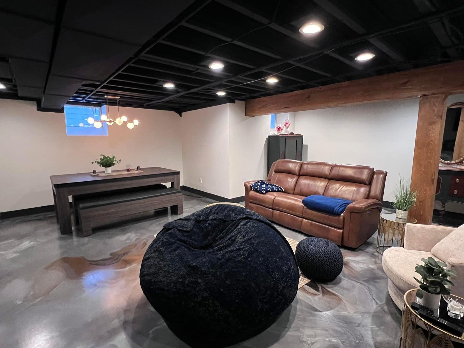 A living room with a couch , table , chairs and bean bag chairs.
