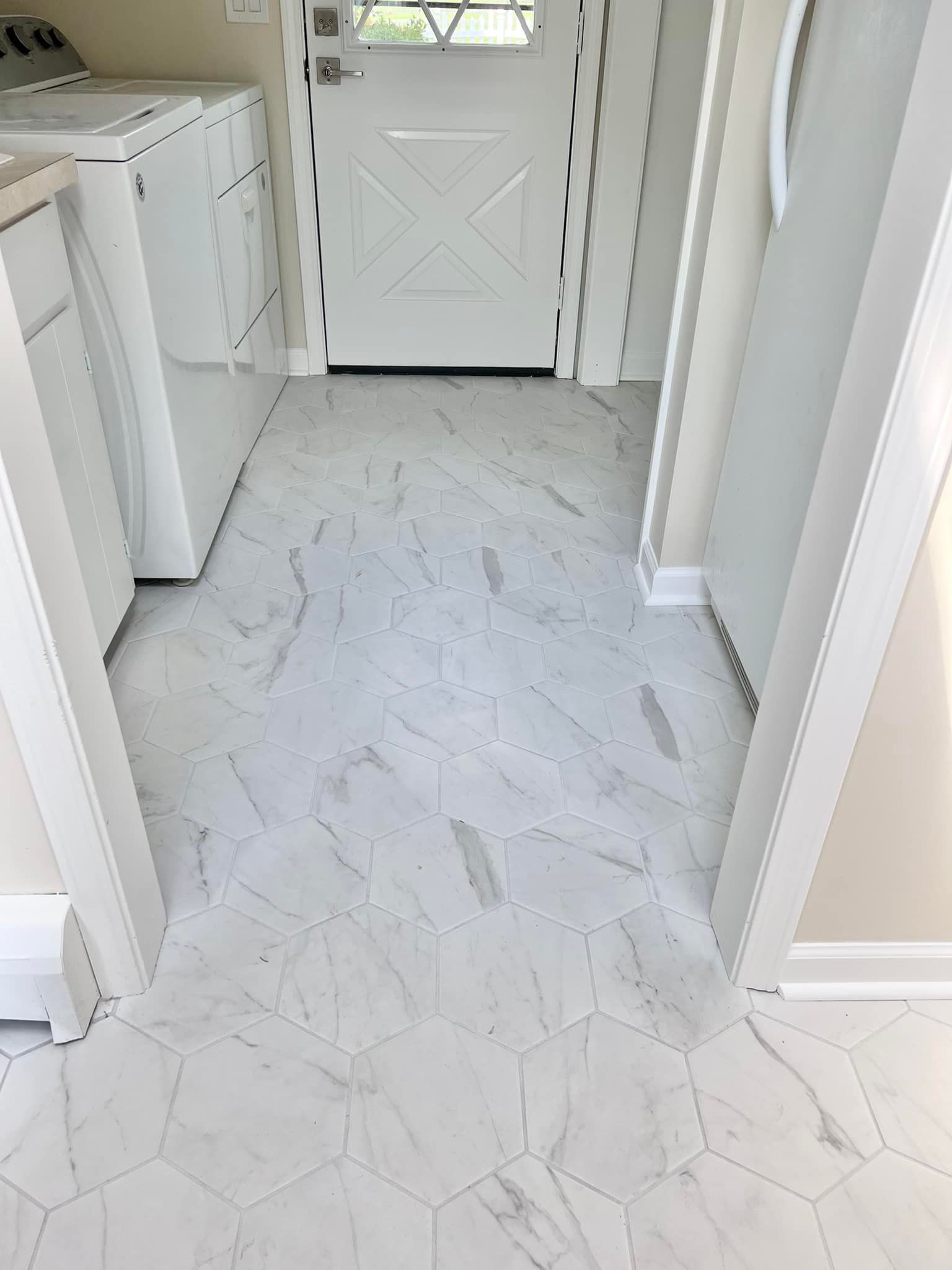 A laundry room with white tile floors and a white door.