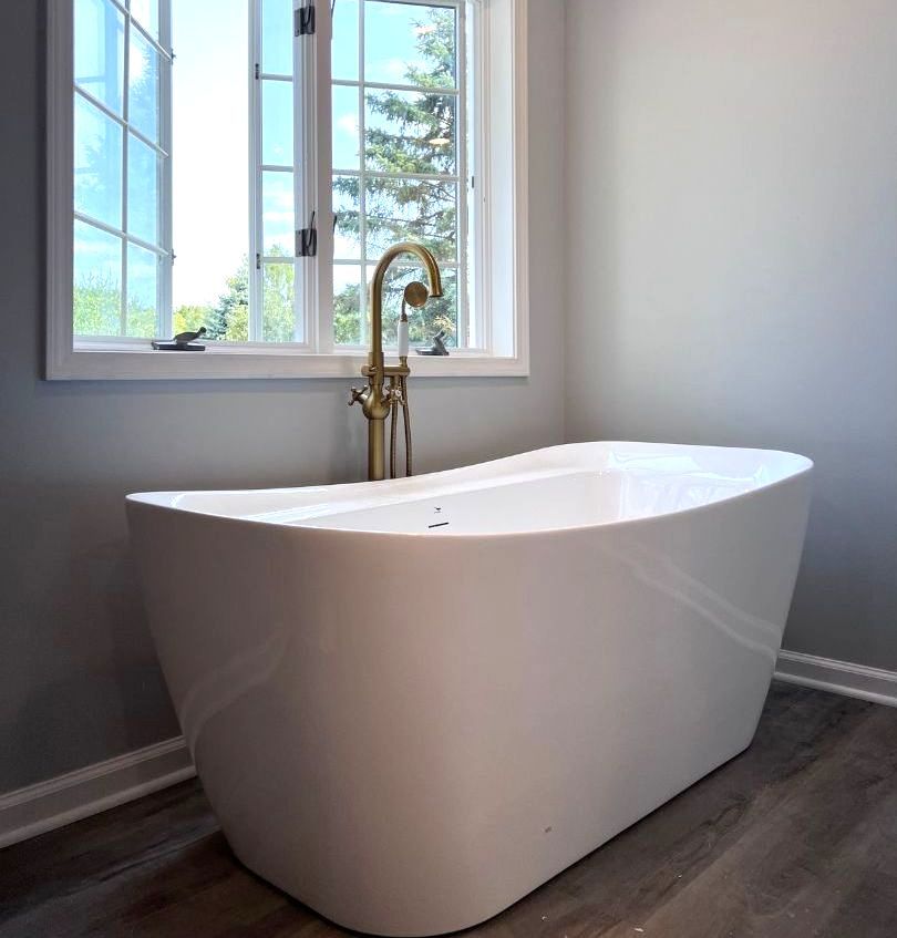 A white bathtub is sitting in a bathroom next to a window.
