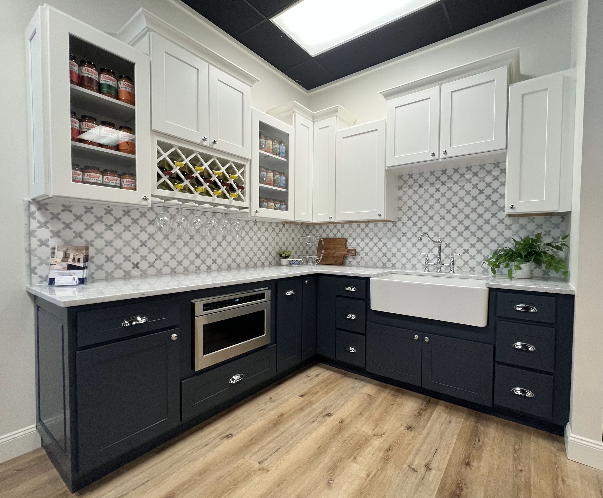 A kitchen with black cabinets , white cabinets , a sink , and a microwave.
