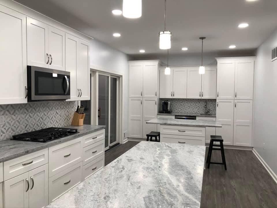 A white house with black shutters is sitting on top of a lush green field.