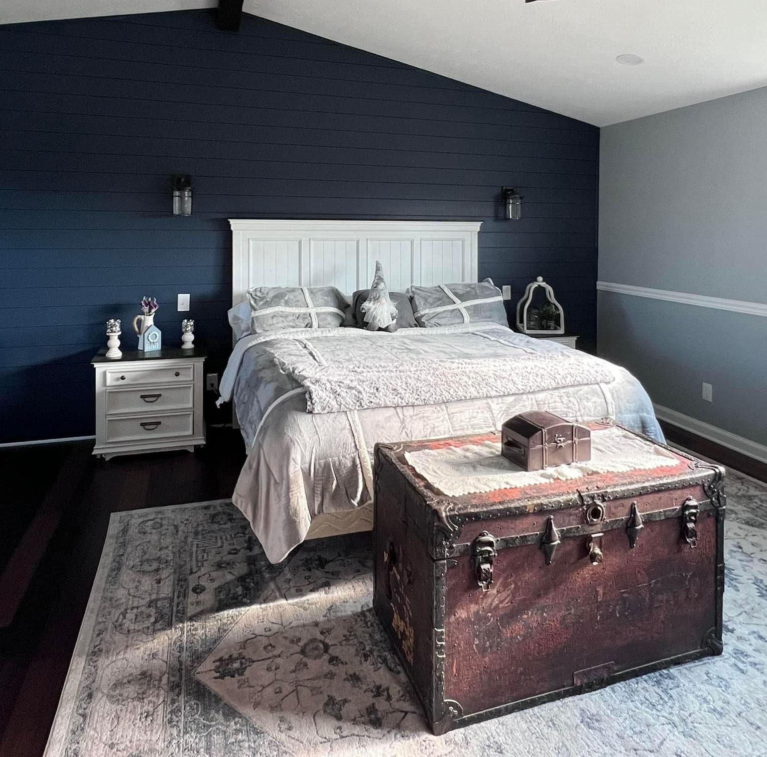 A bedroom with a bed and a trunk on the floor