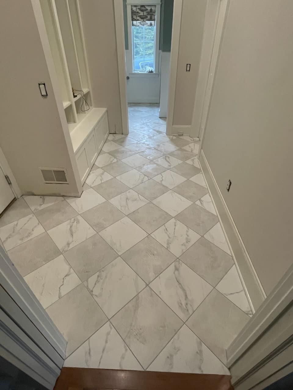 A white house with black shutters is sitting on top of a lush green field.