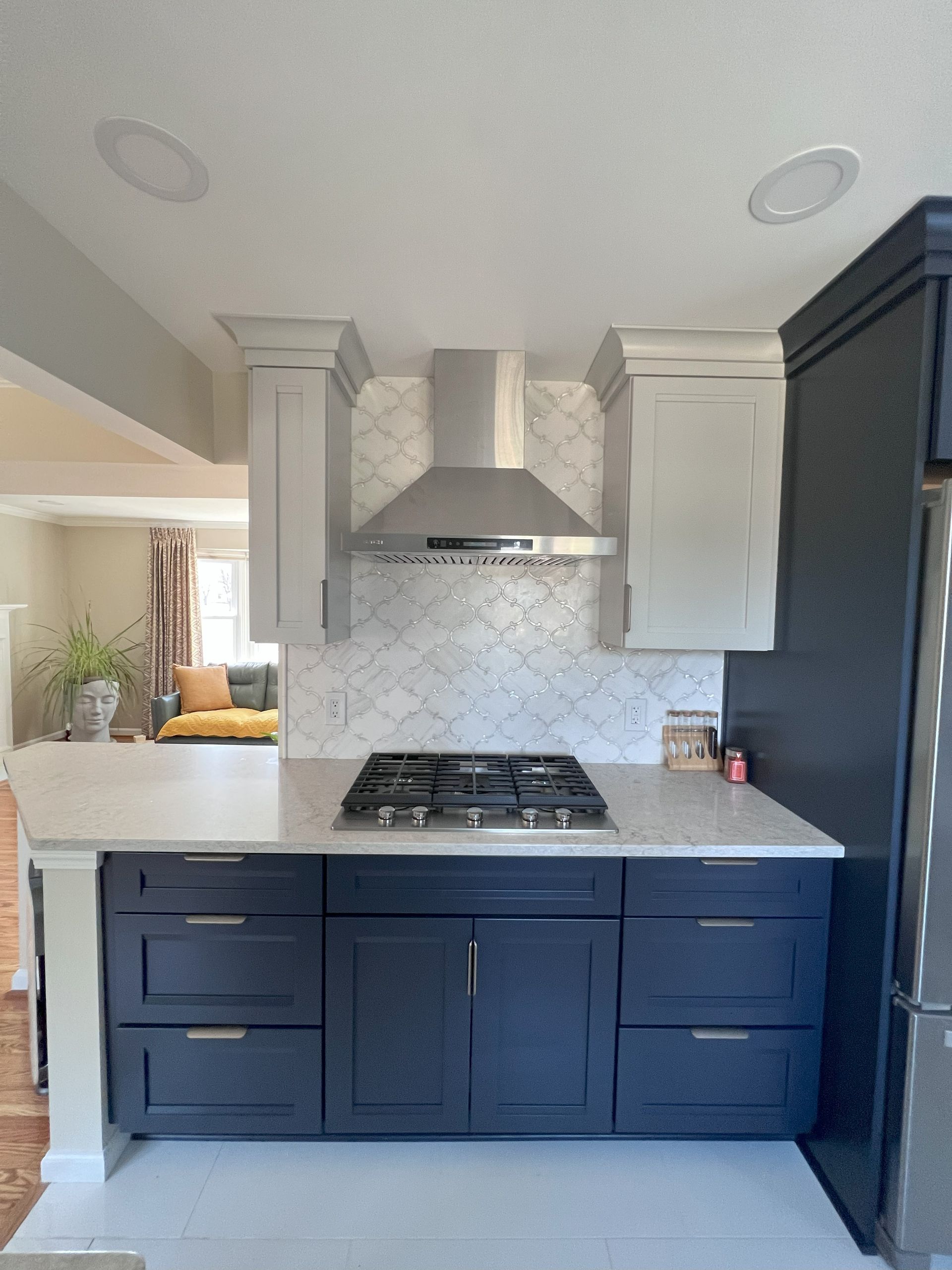 A kitchen with black cabinets and white counter tops and a stove top oven.