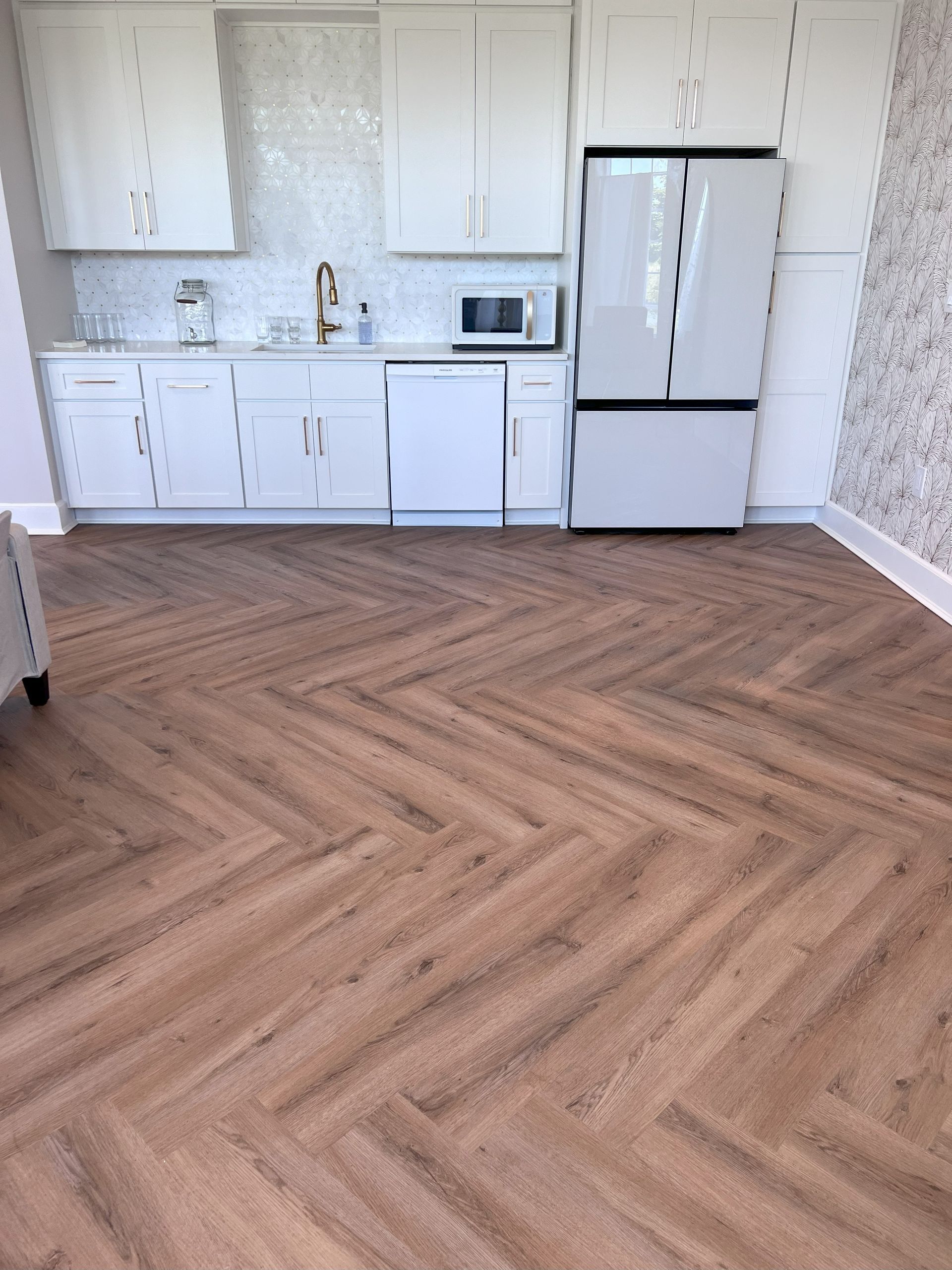 A kitchen with a wooden floor and white cabinets.