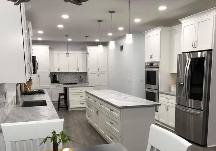 A kitchen with white cabinets and stainless steel appliances and a large island in the middle.