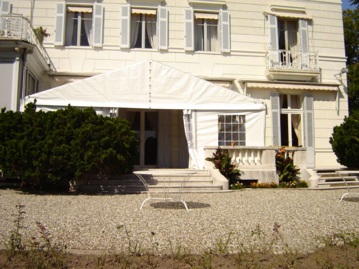 Tente à toit classique blanche sur la terrasse d'une maison blanche