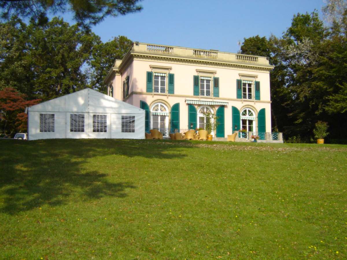 Classic type tent in a garden with a white house in the background
