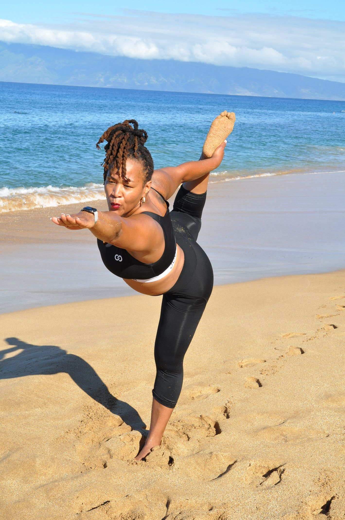 A woman is doing a yoga pose on the beach