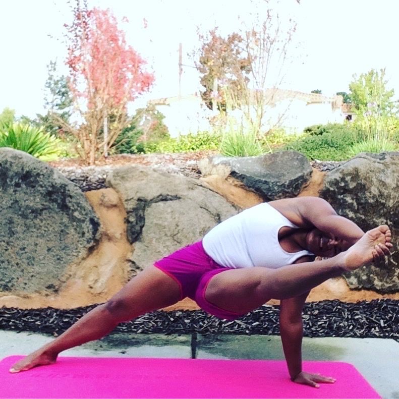 A woman is doing a yoga pose on a pink mat