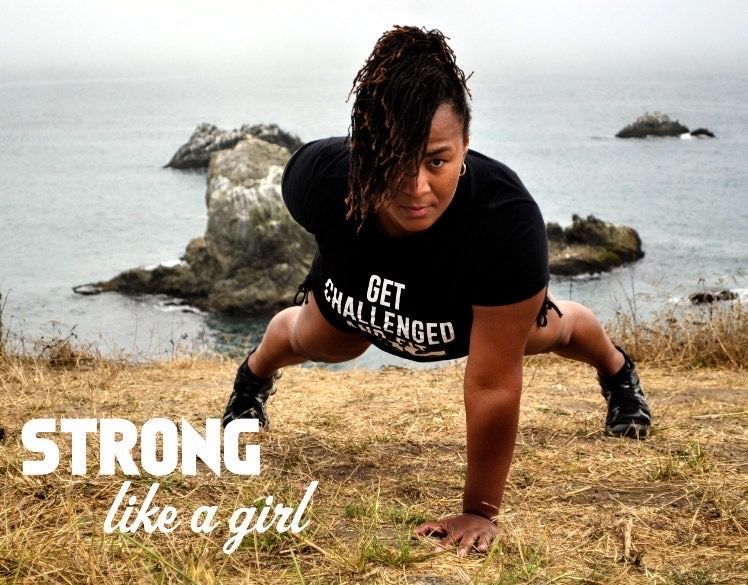 A woman is doing push ups on a hill near the ocean.