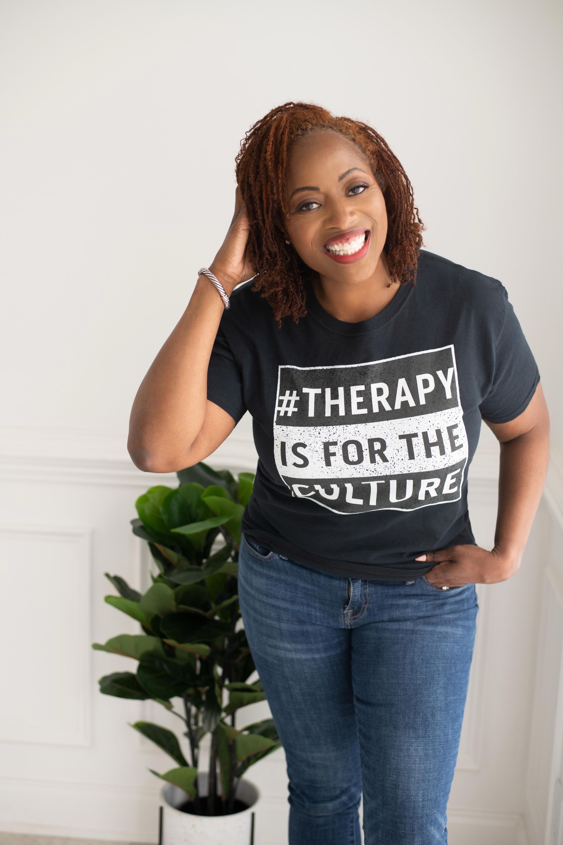 A woman is wearing a black t-shirt that says therapy is for the culture.