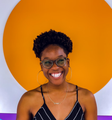 A woman wearing glasses and hoop earrings is smiling for the camera