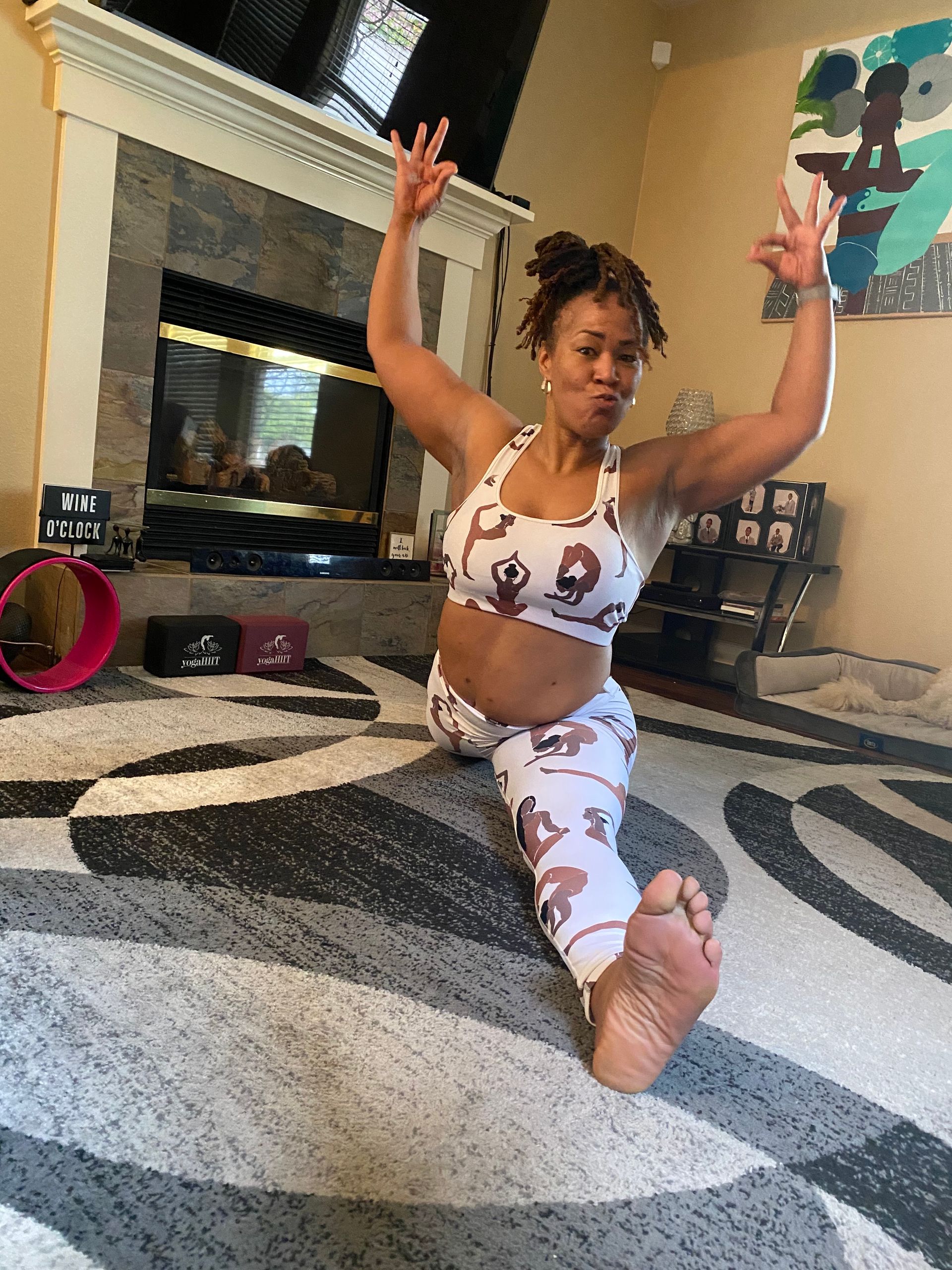 A woman is doing a split on the floor in a living room.